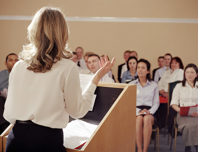 Photograph of a person presenting to a room full of people
